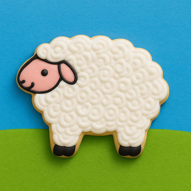 Sheep-shaped cookie with white fur, pink face, and black feet on a blue and green background
