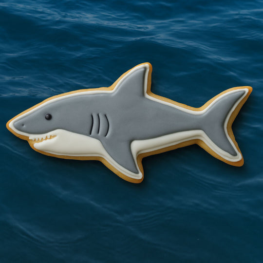 4 inch Shark Metal Cookie Cutter shaped cookie decorated with gray and white icing on a blue ocean background.