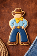 Cookie shaped like a cowboy on a brown leather background from a 4 inch Farmer Cowboy Metal Cookie Cutter
