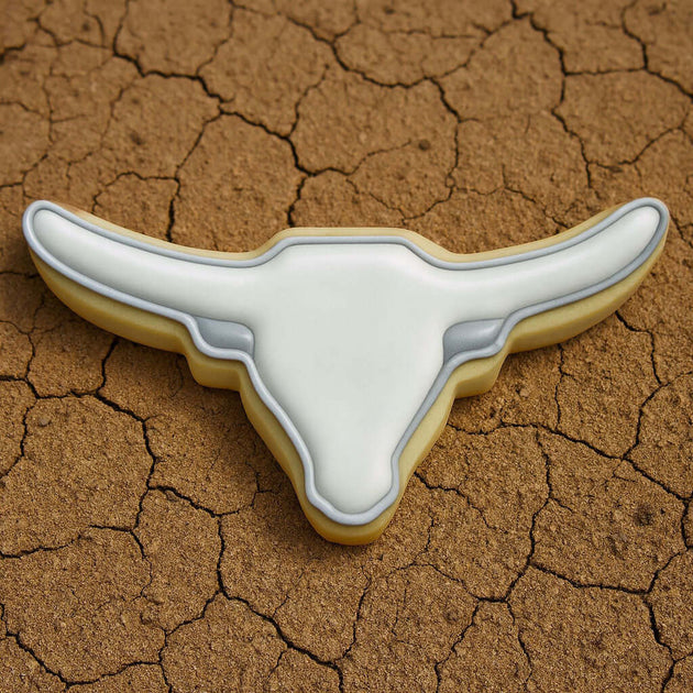 Longhorn-shaped cookie on a cracked brown surface from a 4 inch Longhorn Metal Cookie Cutter