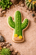 Cactus-shaped cookie with yellow flowers on a sandy surface with cacti and succulents from a 4 inch Cactus Metal Cookie Cutter