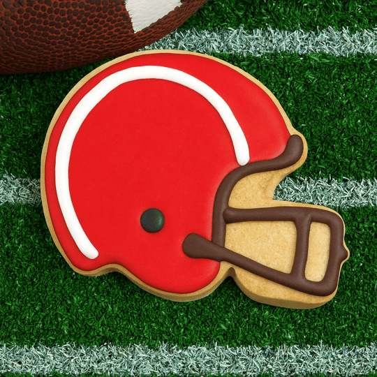 Cookie shaped like a football helmet on grass with a football in the background from a 4.5 inch Football Helmet Metal Cookie Cutter