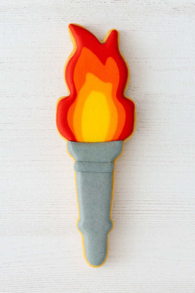 Decorative cookie shaped like a torch with flames on a white background from a 5 inch Torch Metal Cookie Cutter