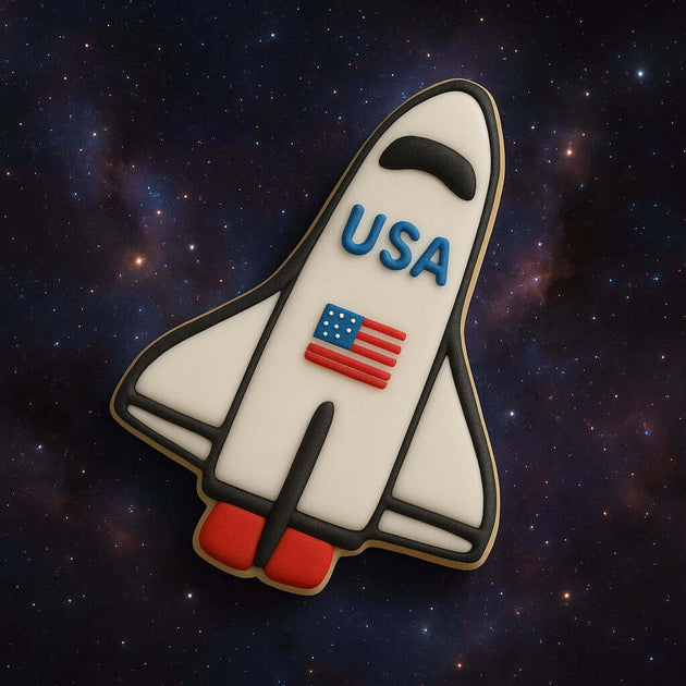 Space shuttle cookie with 'USA' and American flag on a space-themed background from a 4.5 inch Space Shuttle Metal Cookie Cutter