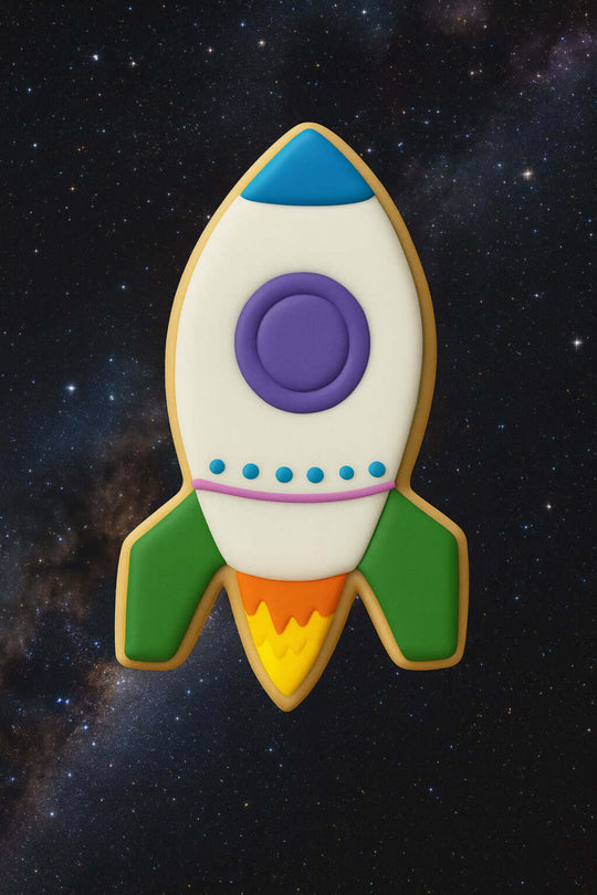 Decorative cookie shaped like a rocket ship on a starry space background from a 4 inch Rocket Ship Metal Cookie Cutter