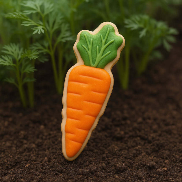 Carrot-shaped cookie with green top on a dark soil background from a 3 inch Carrot Metal Cookie Cutter