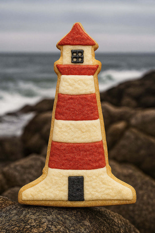 4.5 inch Lighthouse Metal Cookie Cutter shaped cookie on rocks by the ocean.