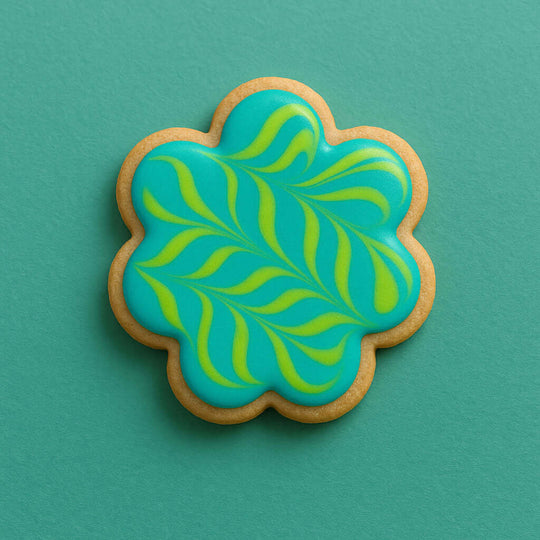 Decorative cookie with blue and green leaf pattern on a teal background