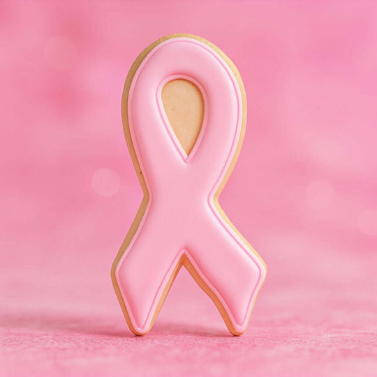 Cookie shaped like a pink breast cancer awareness ribbon on a pink background