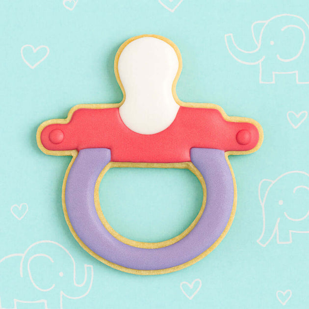 Cookie-shaped pacifier on a light blue background with heart and elephant designs from a 3 inch Baby Pacifier Metal Cookie Cutter