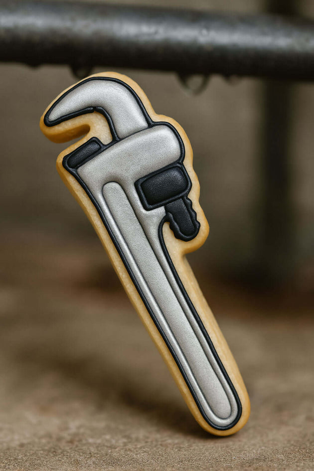 5.75 inch Pipe Wrench Metal Cookie Cutter shaped cookie against a rustic background.