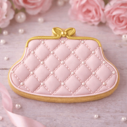 Pink quilted purse cookie with gold accents on a light wooden surface with pink roses and pearls from a 4 inch Purse Metal Cookie Cutter