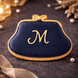 Navy blue clutch with gold trim and 'M' monogram on a dark background from a 4 inch Purse Metal Cookie Cutter