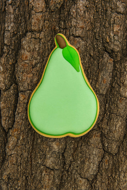 Green pear-shaped cookie on a tree trunk from a 3.25 inch Pear Metal Cookie Cutter
