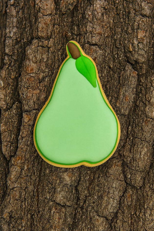 Green pear-shaped cookie on a tree trunk from a 3.25 inch Pear Metal Cookie Cutter
