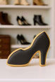 Black high-heeled shoe cookie on a white surface with shoes in the background
