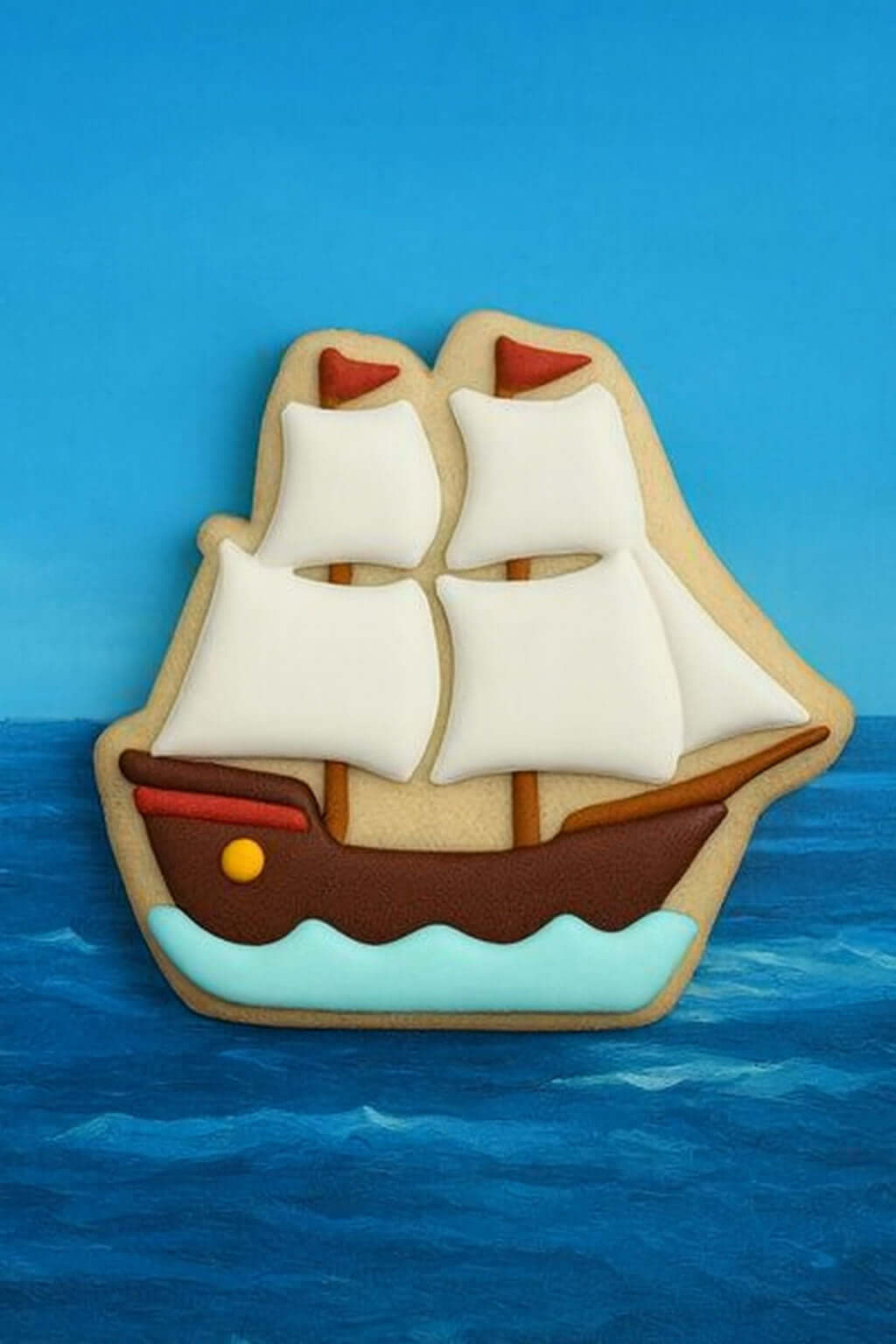 Decorative cookie shaped like a ship with sails on a blue background from a 4.25 inch Pirate Tall Sailing Ship Metal Cookie Cutter