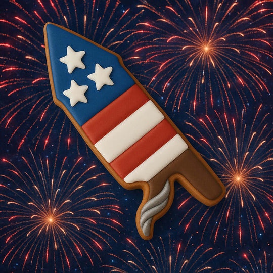 Cookie shaped like a bottle rocket with stars and stripes against a fireworks background