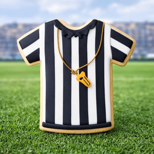 Referee shirt decorated sugar cookie made with a 4 inch T Shirt Metal Cookie Cutter on a sports field background