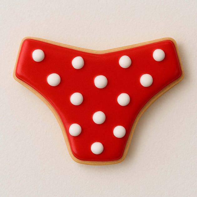 Decorative cookie shaped like a bikini bottom, featuring red icing with white polka dots, perfect for summer treats from a 4 inch Bikini Bottom Metal Cookie Cutter