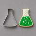 A metal  flask-shaped cookie cutter shown next to a decorated sugar cookie in the shape of a flask, filled with green and white icing and topped with white bubble details, on a solid gray background from a 4 inch Beaker Metal Cookie Cutter