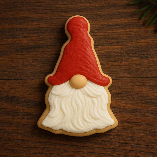 Cookie shaped like a gnome with a red hat and white beard on a wooden surface from a 5 inch Gnome Metal Cookie Cutter