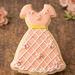 Cookie shaped like a dress with pink icing and floral decorations on a wooden surface from a 4 inch Dress Metal Cookie Cutter
