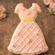 Cookie shaped like a dress with pink icing and floral decorations on a wooden surface from a 4 inch Dress Metal Cookie Cutter