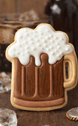 Cookie shaped like a beer mug with white foam on a wooden surface from a 4 inch Root Beer Mug Metal Cookie Cutter