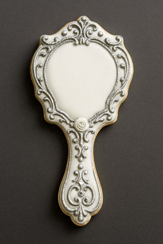 Decorative cookie shaped like a hand mirror on a dark background from a 4.5 inch Hand Mirror Metal Cookie Cutter