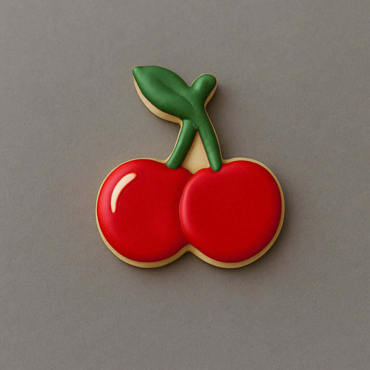 Cookie shaped like a cherry on a gray background from a 3.5 inch Cherries Metal Cookie Cutter