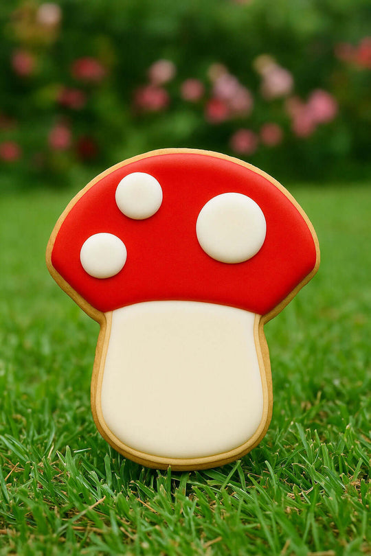 Mushroom-shaped cookie on grass with blurred flowers in the background