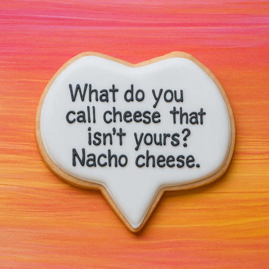 Talk bubble-shaped cookie with text 'What do you call cheese that isn't yours? Nacho cheese.' on a colorful background