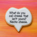 Talk bubble-shaped cookie with text 'What do you call cheese that isn't yours? Nacho cheese.' on a colorful background