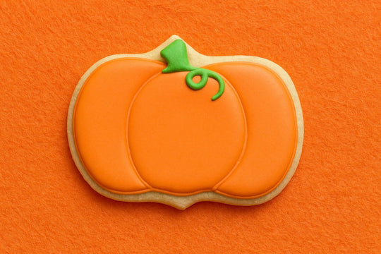 Pumpkin-shaped cookie with green stem on an orange background from a 5.5 inch Plaque or Frame Metal Cookie Cutter