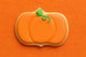 Pumpkin-shaped cookie with green stem on an orange background from a 5.5 inch Plaque or Frame Metal Cookie Cutter