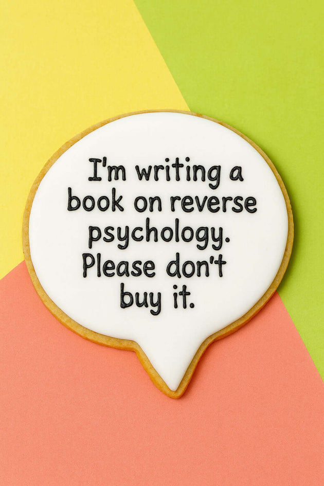 Cookie with text 'I'm writing a book on reverse psychology. Please don't buy it.' on a colorful background