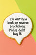 Cookie with text 'I'm writing a book on reverse psychology. Please don't buy it.' on a colorful background