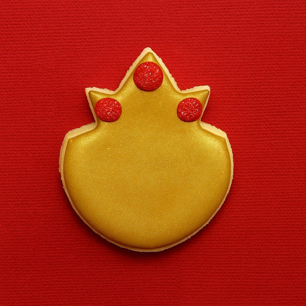 Gold cookie with red decorations on a red background from a 3.75 inch Pineapple Metal Cookie Cutter
