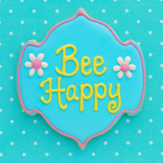 Decorative cookie with 'Bee Happy' text on a blue background with white polka dots from a 5 inch Plaque or Frame Metal Cookie Cutter