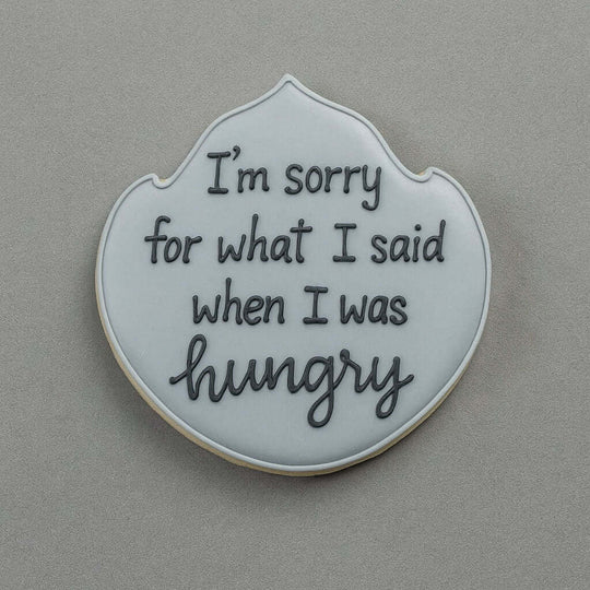 Cookie with text 'I'm sorry for what I said when I was hungry' on a gray background