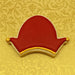 Decorative cookie shaped like a red hat with gold accents on a yellow patterned background