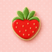 Strawberry-shaped cookie with green leaves on a pink polka dot background from a 3.5 inch Strawberry Metal Cookie Cutter