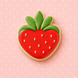 Strawberry-shaped cookie with green leaves on a pink polka dot background from a 3.5 inch Strawberry Metal Cookie Cutter