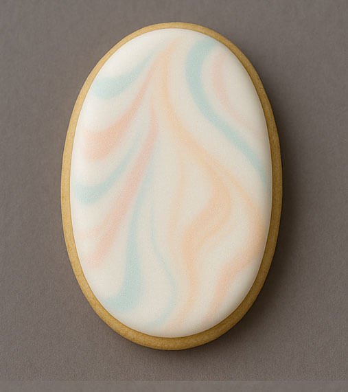 4 inch Oval Metal Cookie Cutter decorated cookie with pastel swirl design on a neutral background.