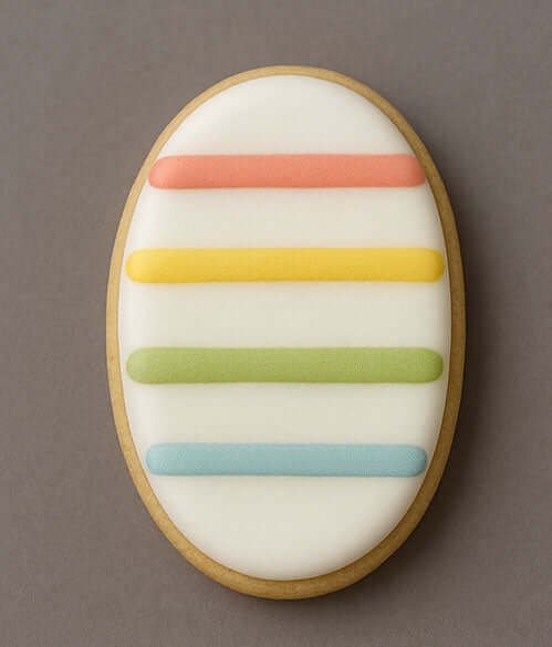 A beautifully decorated cookie featuring an oval shape with colorful stripes, created using a 4.5 inch Oval Metal Cookie Cutter.