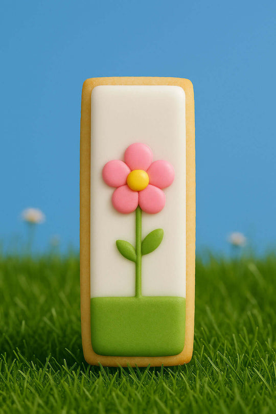 Decorative cookie with a pink flower on a grassy background