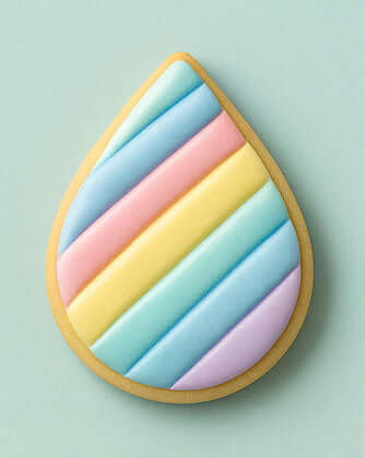 Teardrop-shaped cookie with pastel color stripes on a light green background from a 2.5 inch Tear Drop Rain Flower Petal Metal Cookie Cutter