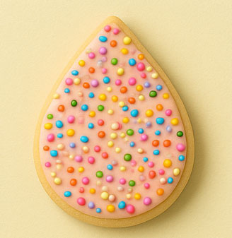 Teardrop-shaped cookie with pink frosting and colorful sprinkles on a light yellow background.