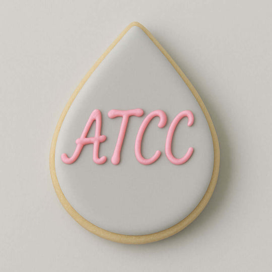 Teardrop-shaped cookie with 'ATCC' in pink icing on a light gray background